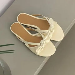 Feminine bow detail sandals, white sandals with bow details on a light grey surface