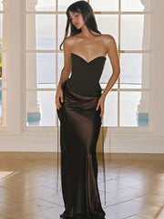 Editorial shot of brown strapless satin dress styled against white setting