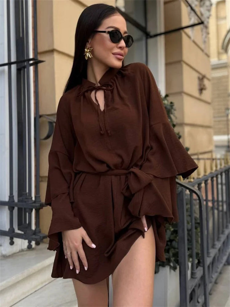 Woman wearing chocolate brown ruffle mini dress with lace-up neckline