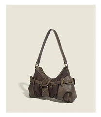 Slouchy brown Y2K underarm purse with buckle details and zipper closure on a beige background
