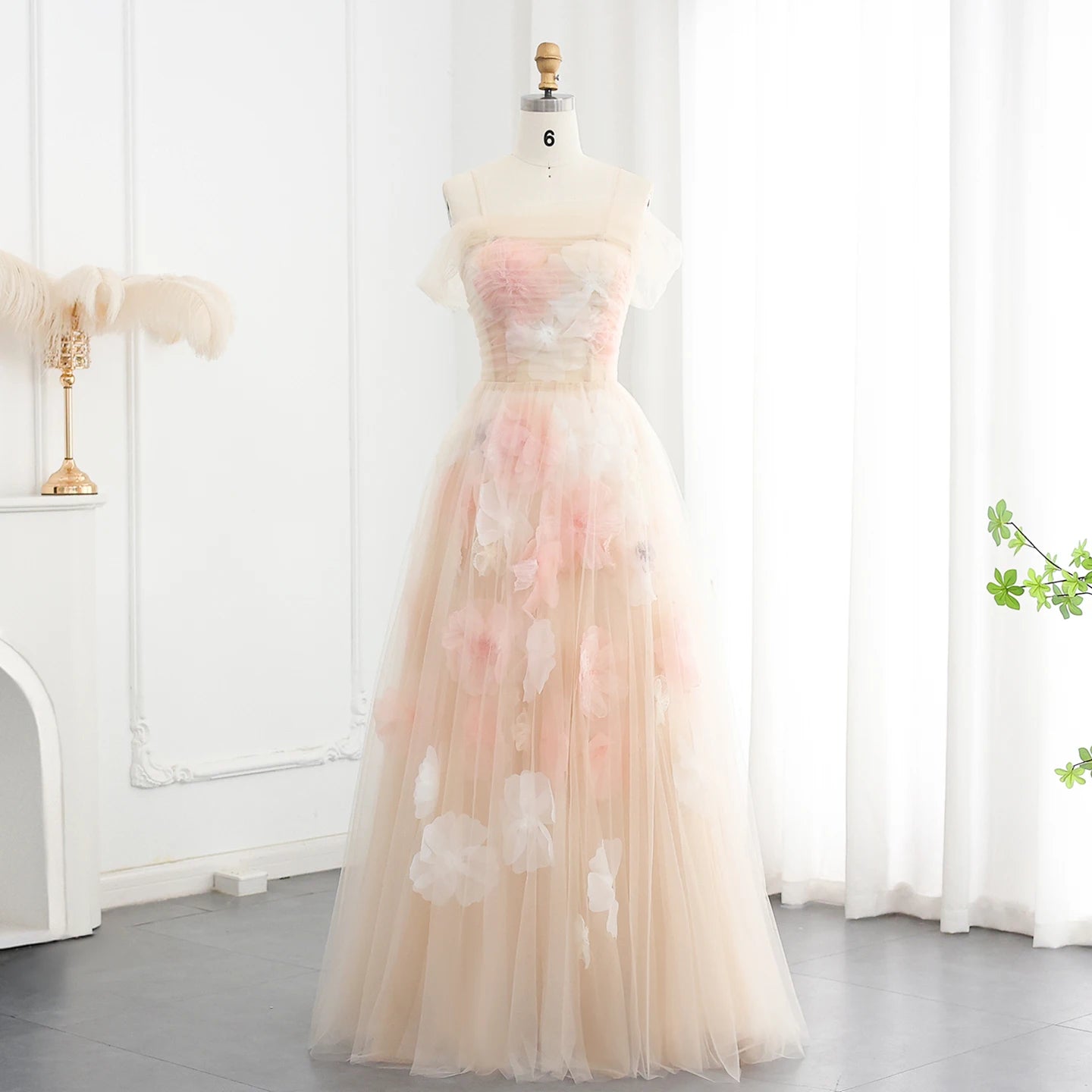 A close-up of the delicate floral appliqués and ruffles on the champagne tulle fabric.