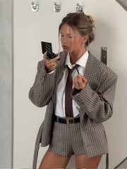 Mirror selfie showing a checkered blazer and matching shorts set, styled with a white shirt, slim tie, and minimal accessories.