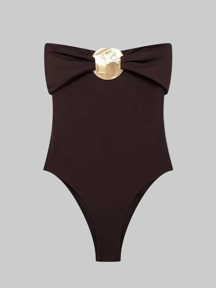 Dark brown off-shoulder bodysuit on a light background, featuring a folded neckline and a central gold-toned metal accent at the bust