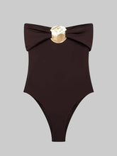 Dark brown off-shoulder bodysuit on a light background, featuring a folded neckline and a central gold-toned metal accent at the bust
