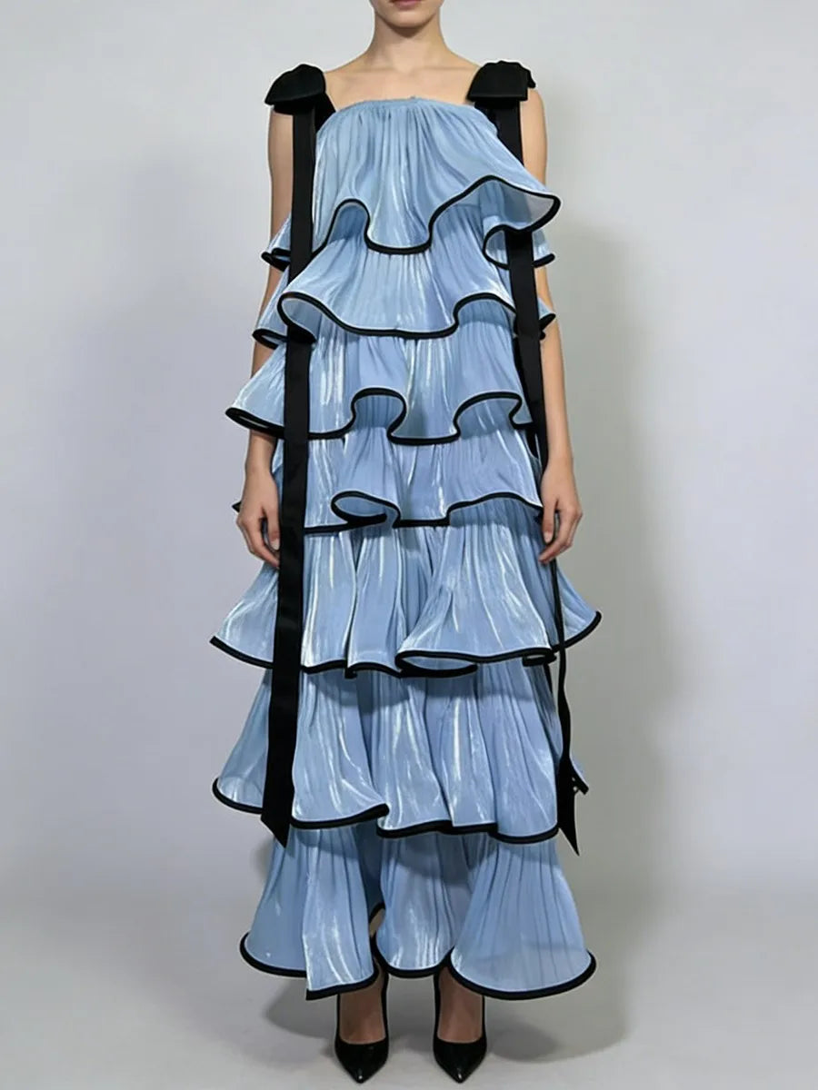 Full length editorial pose showing structured multi layer ruffles, square neck bodice and bow accent paired with pointed heels