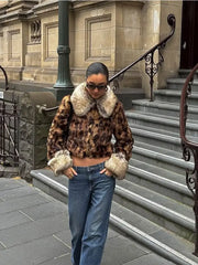Person wearing a leopard print coat with fur trim on a city street.