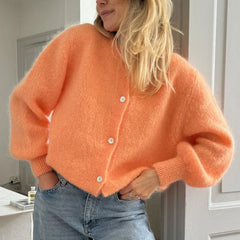 Cozy open-stitch orange cardigan paired with blue jeans indoors