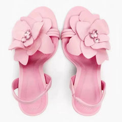 Designer pink floral thin heel sandals showcased against a white background. Pair of pink sandals with floral designs on a white background