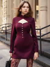Tailored blazer mini dress with a high collar and cut-out detail styled in a city setting for an elegant evening look.