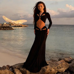 Model wearing a black long sleeve cutout crop top with a matching floor-length maxi skirt for a sleek resort look.