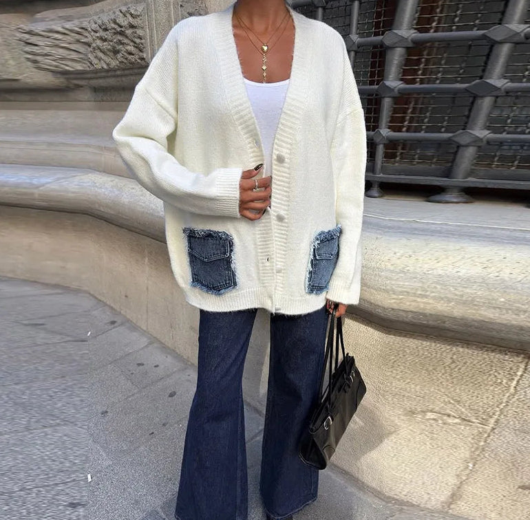 Close-up of the cream knit showing the denim pocket patchwork, button placket, and ribbed trim texture in crisp natural light.