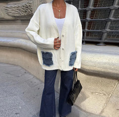 Close-up of the cream knit showing the denim pocket patchwork, button placket, and ribbed trim texture in crisp natural light.