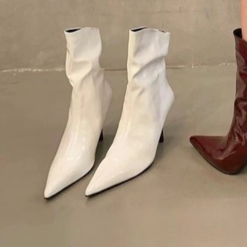 Designer autumn white patent boots photographed on minimalist neutral background