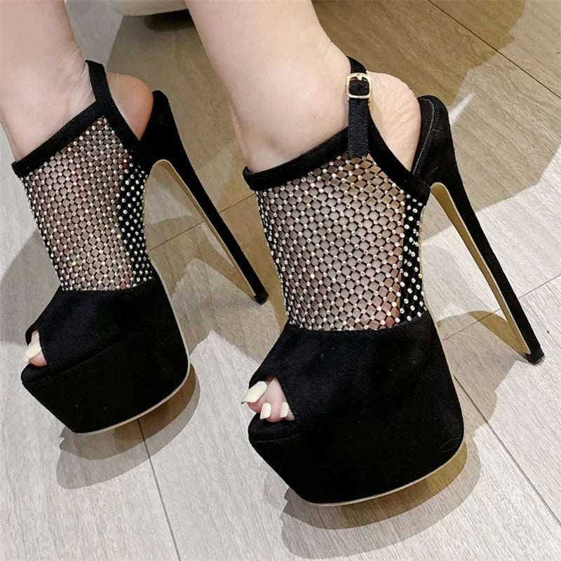 Black high-heeled shoes with mesh design on a wooden floor
