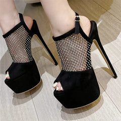 Black high-heeled shoes with mesh design on a wooden floor