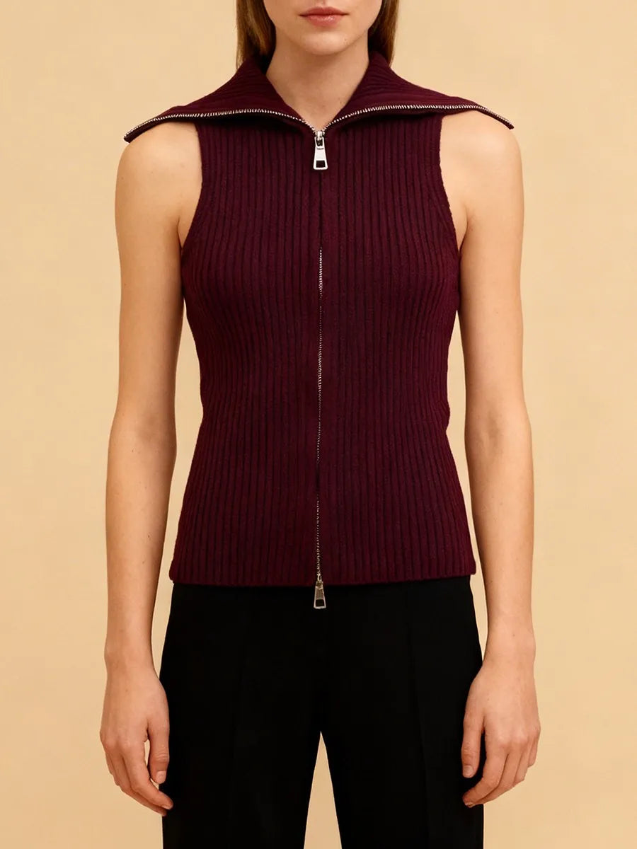 Model wearing a sleeveless knit top with double zipper detail, standing against a soft studio backdrop