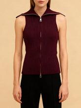 Model wearing a sleeveless knit top with double zipper detail, standing against a soft studio backdrop