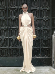 Lower-skirt detail showing the flowing drape and ankle-length hem pooling lightly, emphasizing the dress’s elongated sheath silhouette.