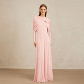 Model wearing a long sleeve maxi gown with a draped shawl neckline, standing against a clean studio wall with a poised stance.