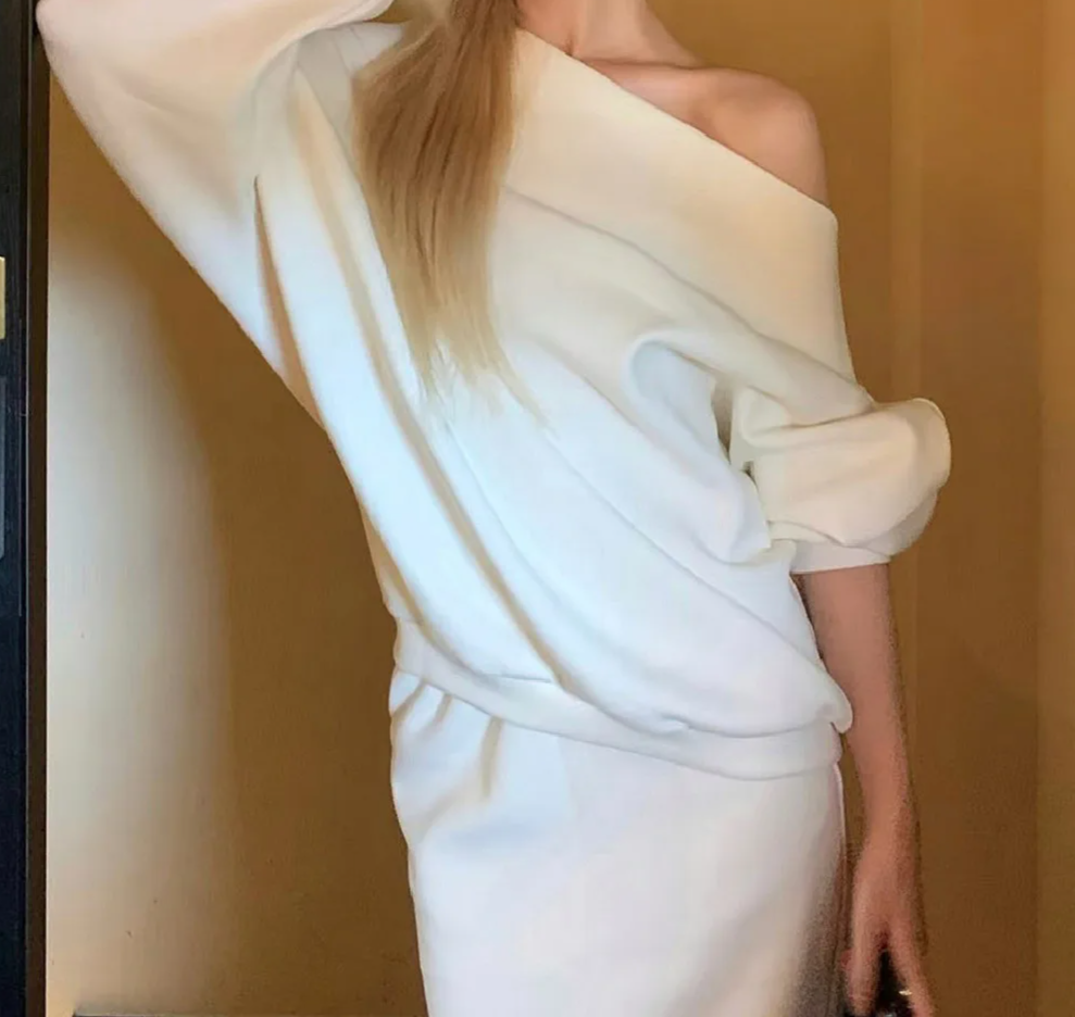 White off-shoulder top worn by a person against a plain background