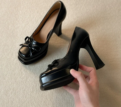 Close-up of black platform dress pumps showing bow detail
