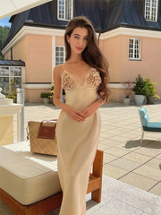 Woman in a beige evening gown with floral details standing outdoors.