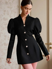 Editorial shot of a black puff sleeve dress styled indoors.