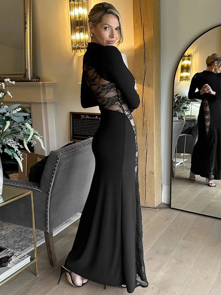 Woman in a black evening gown with sheer details standing in a stylish room.