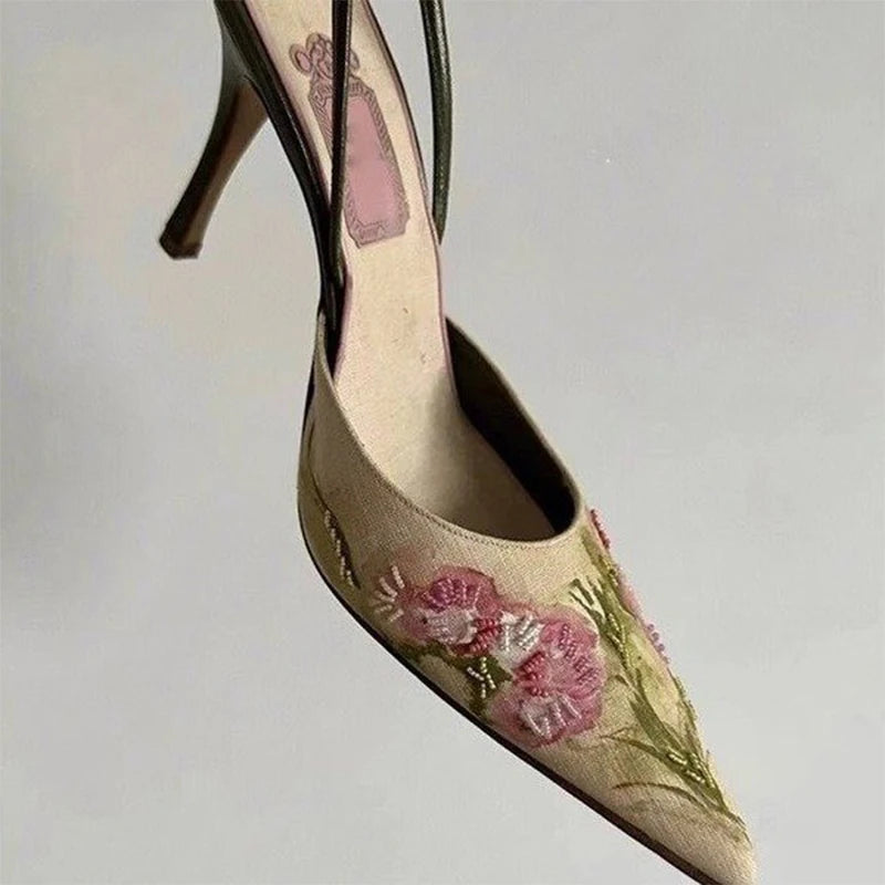 High-heeled shoe with floral embroidery on a light gray background