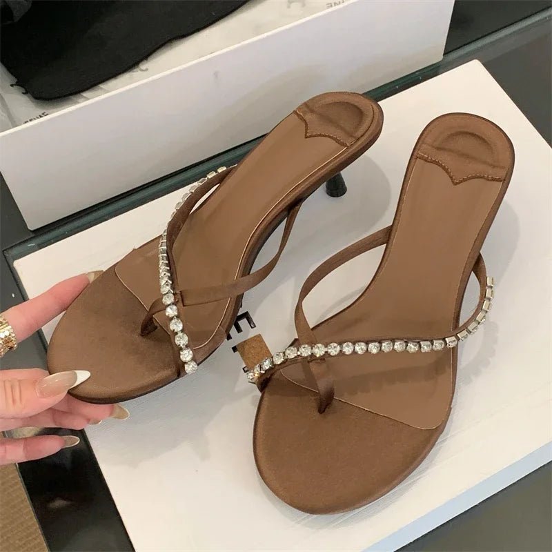 Brown sandals with embellishments on a white surface