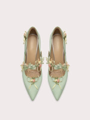 Elegant mint green dress pump with flower applique styled for seasonal celebrations on a light grey background