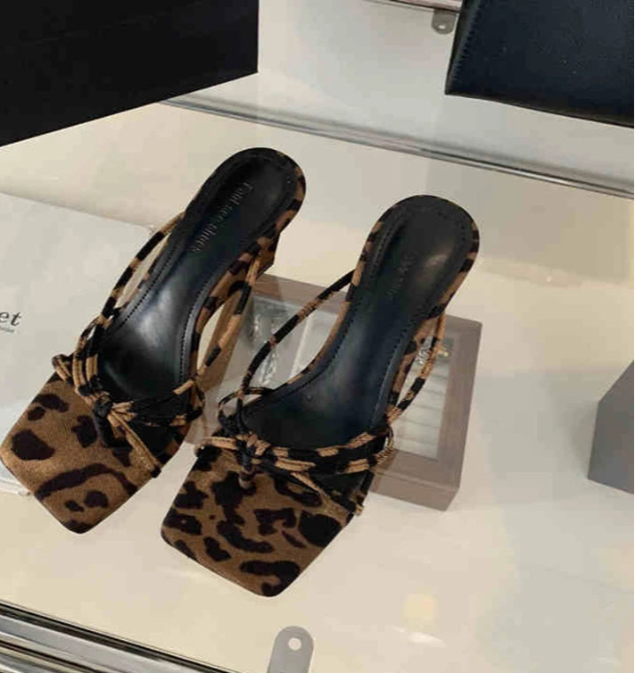 Close-up of leopard wedge heel party slides on neutral floor