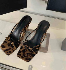 Close-up of leopard wedge heel party slides on neutral floor