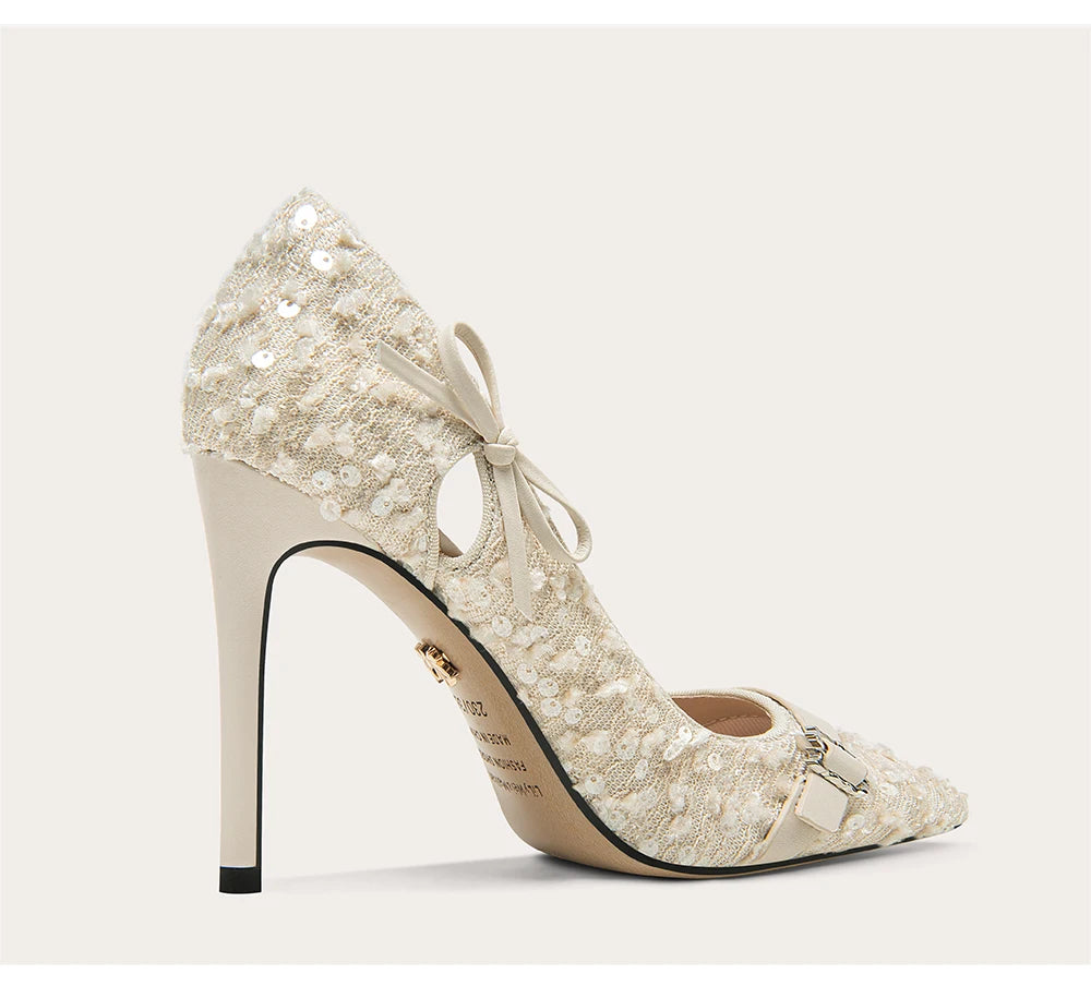 Beige lace high-heeled shoe with bow on a light gray background