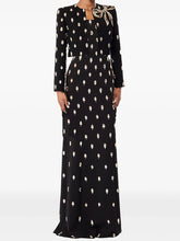 Model wearing a maxi dress with an all-over embellished motif and a cropped blazer, styled as a coordinated formal set on a studio background.