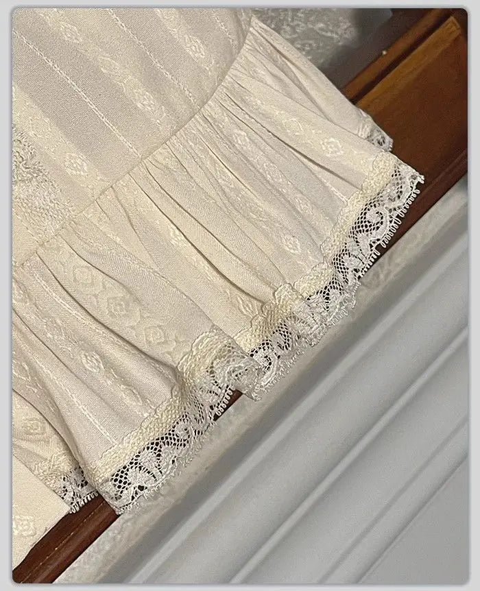 Close-up of the ruffled lace hem on a cream blouse