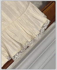 Close-up of the ruffled lace hem on a cream blouse