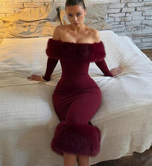 Indoor editorial styling of an off-shoulder midi dress with faux fur trim and sculpted evening silhouette sitting on a bed.