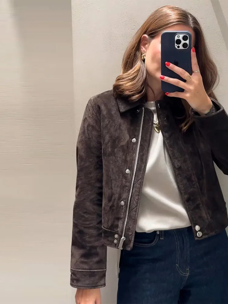 Person wearing a dark brown suede jacket taking a mirror selfie.
