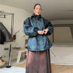Person wearing a plaid raincoat in a room with furniture and decor.