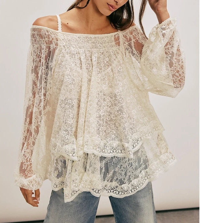 A woman modeling a floral lace sheer blouse worn off the shoulder.