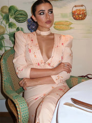 Woman in a floral dress sitting on a chair with a decorative background