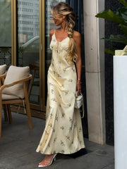 woman in a floral satin spaghetti strap slip maxi dress outside a café