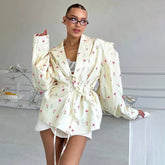 Floral waist-tie blazer worn by woman indoors in relaxed pose