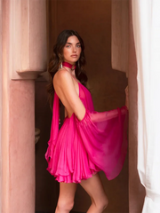 Woman in a lightweight A-line mini dress that moves easily when you walk standing in a doorway with architectural columns.