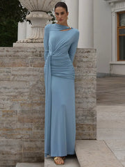 A woman in a formal long-sleeve evening dress in light blue is shown outdoors for women standing in front of a stone wall and classical architecture.