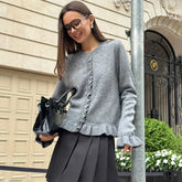 Woman wearing frill trim knit cardigan styled with pleated skirt on a city street