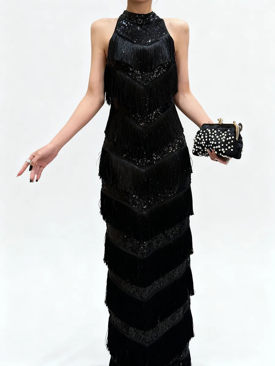 Detail view of the black dress showing chevron-like tassel tiers that add texture and movement across the skirt.
