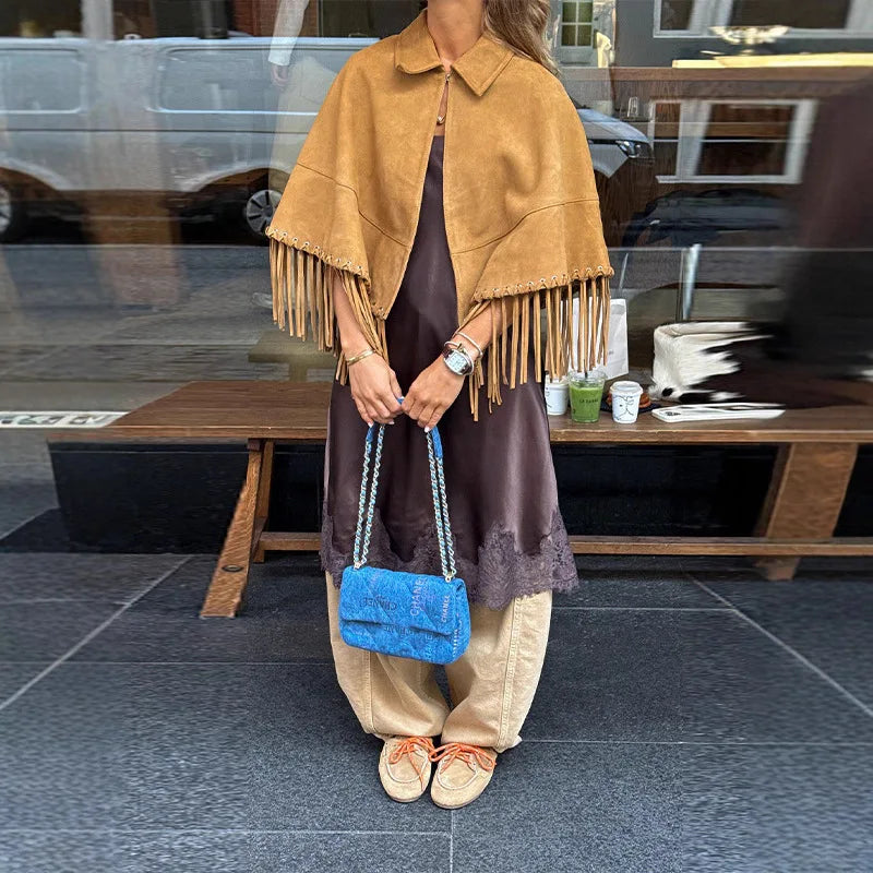 Model wearing a fringe hem cape coat with a turn-down collar and single-button front, styled as a polished layering piece.
