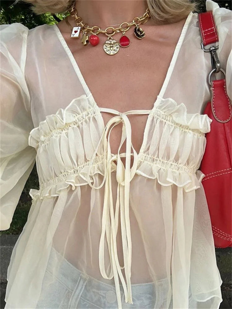 Close-up of a person wearing a white blouse with ruffled details and a red handbag.